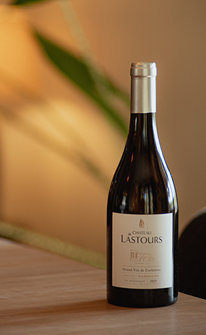 Bouteille de vin rouge du Château de Lastours posée sur une table en bois