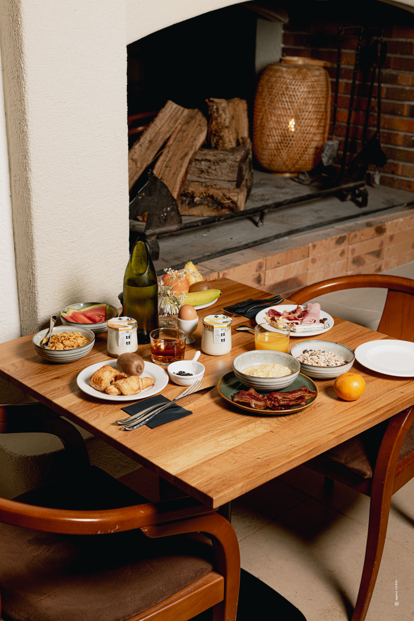 Petit-déjeuner complet dressé sur une table en bois près d'une cheminée