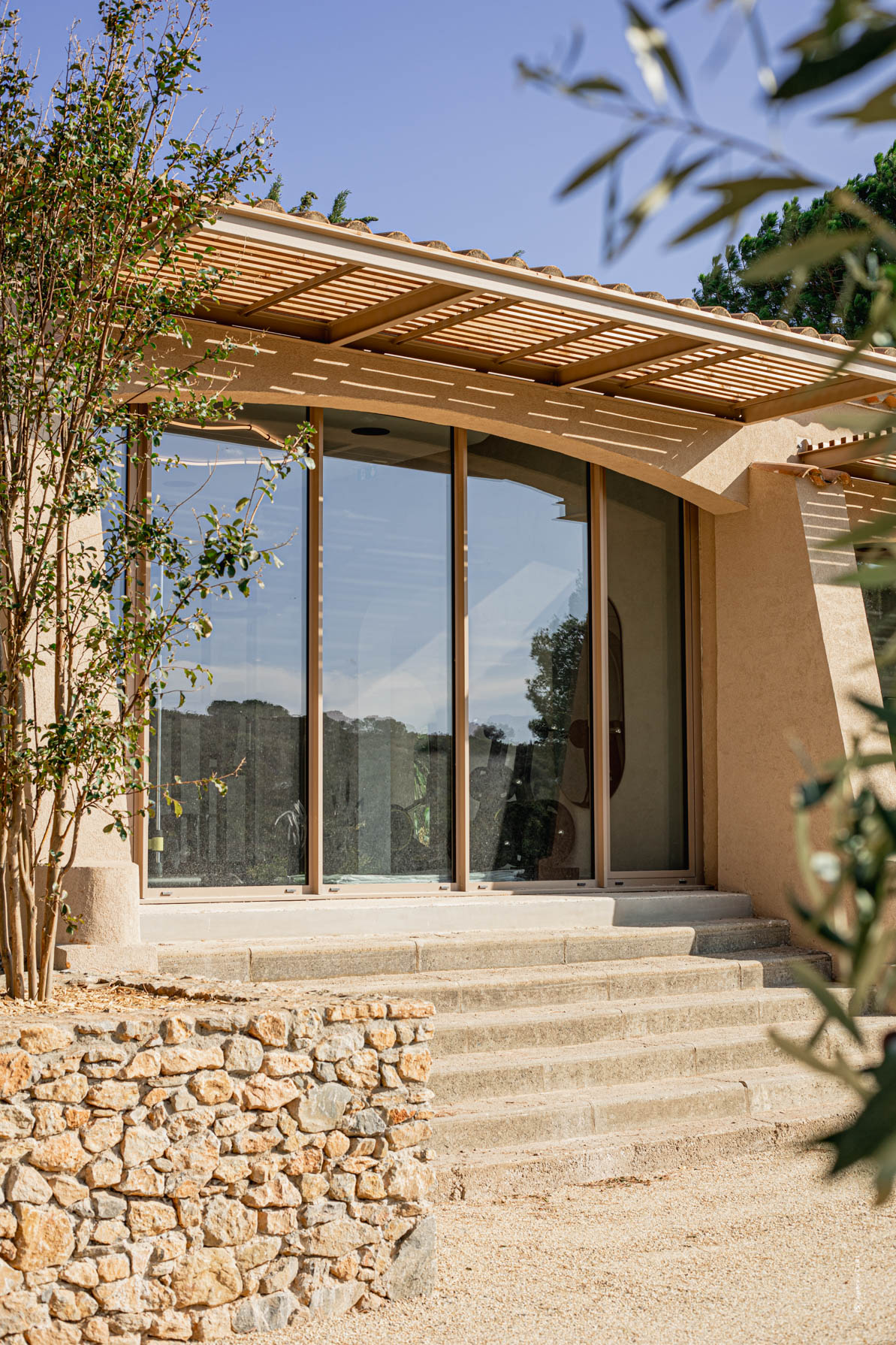 Entrée vitrée d’un bâtiment avec auvent en bois au Château de Lastours