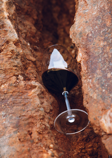 Verre de vin rouge du Château de Lastours posé entre deux roches ocres
