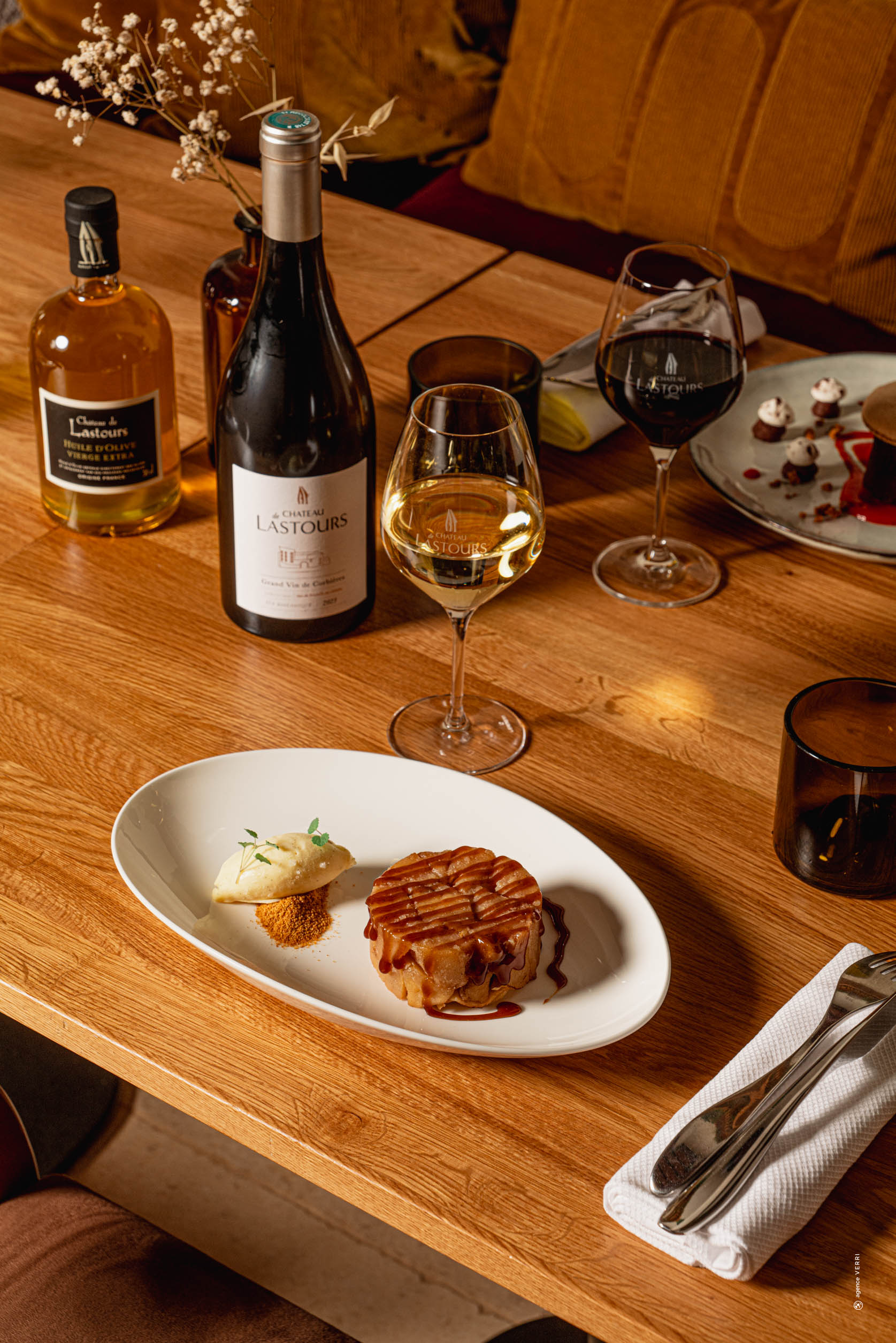 Dessert gourmand au caramel avec glace vanille, servi avec un verre de vin blanc Château de Lastours sur une table de restaurant raffinée.