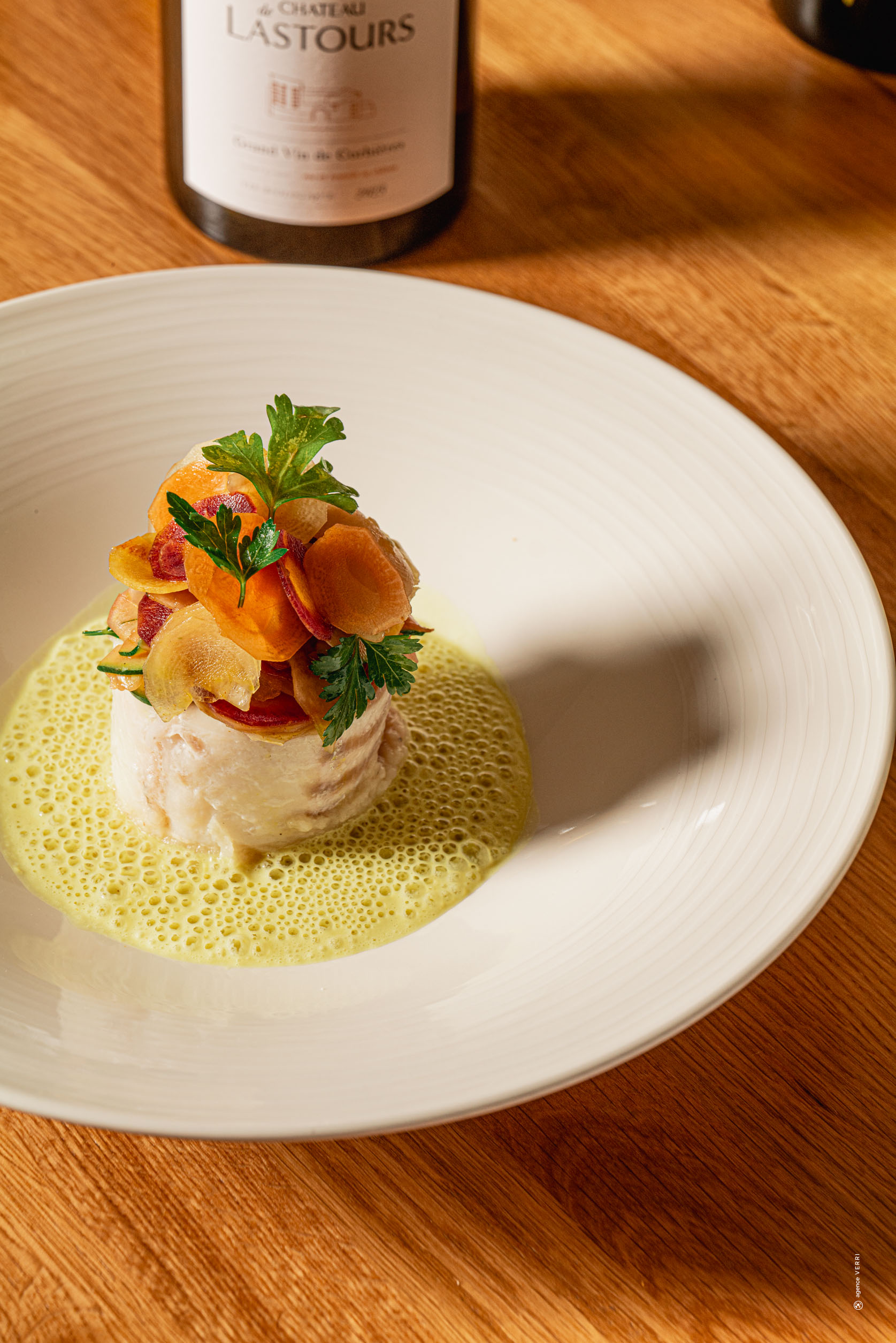 Plat gastronomique à base de poisson et légumes croquants, accompagné d’un vin blanc du Château de Lastours