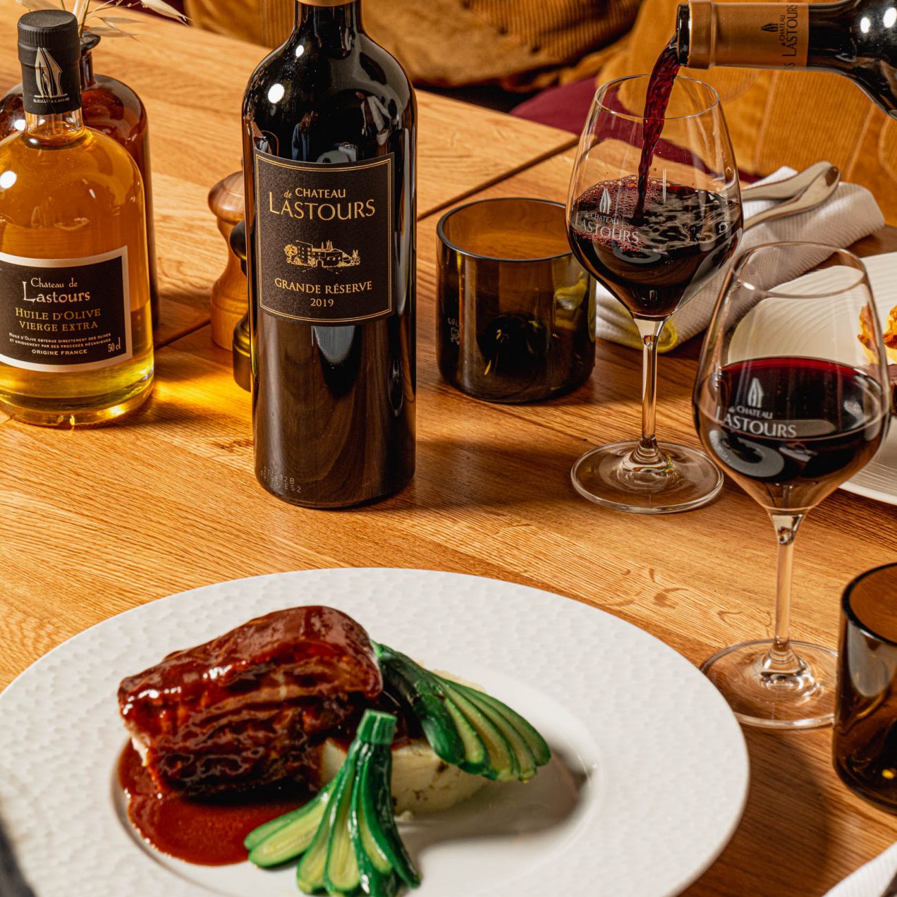 Plat gastronomique de viande en sauce avec purée et légumes verts, accompagné d’un verre de vin rouge Château de Lastours Grande Réserve 2019 servi à table.