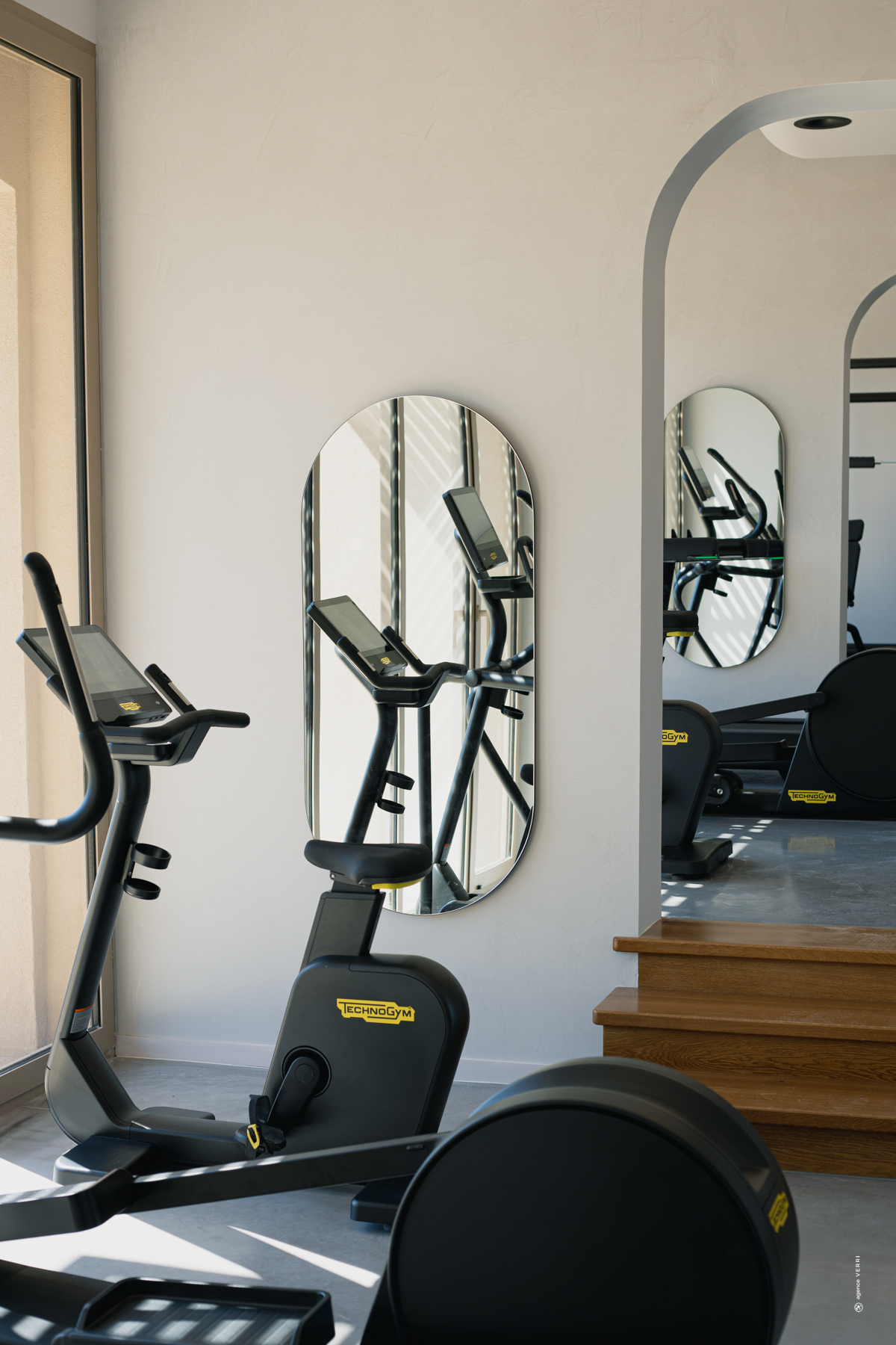 Salle de sport moderne au Château de Lastours avec équipements Technogym et ambiance lumineuse