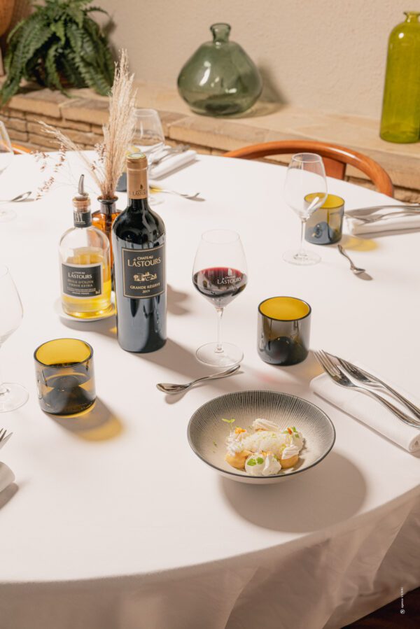 Table dressée au Château de Lastours avec vin rouge Grande Réserve, huile d’olive et dessert gastronomique